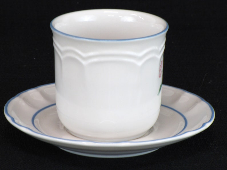 May include: A white ceramic teacup and saucer set with a blue rim and a pink floral design.