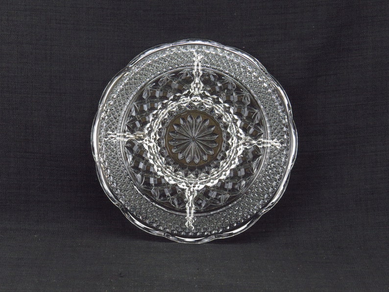 May include: A clear glass serving dish with a diamond pattern and four sections. The dish has a scalloped edge.
