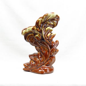Könnte beinhalten: Eine braune und cremefarbene Keramikvase in Form eines stilisierten Blattes. Die Vase hat eine glänzende Oberfläche und ist mit erhabenen Details verziert.