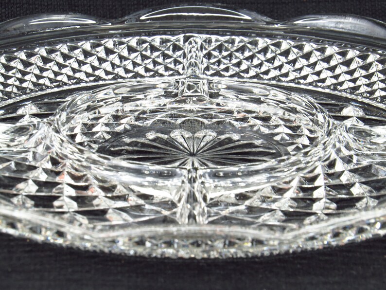 May include: A clear glass serving dish with a diamond pattern. The dish has four sections and a centre well.