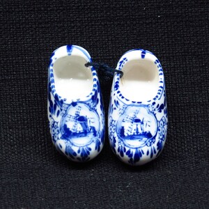 Könnte beinhalten: Paar blaue und weiße Keramik-Klompen-Figuren mit Windmühlenmotiven.