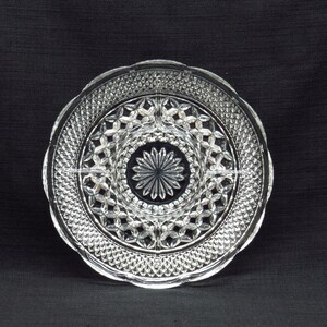 May include: A clear glass serving dish with a decorative, diamond-shaped pattern. The dish is divided into four sections.