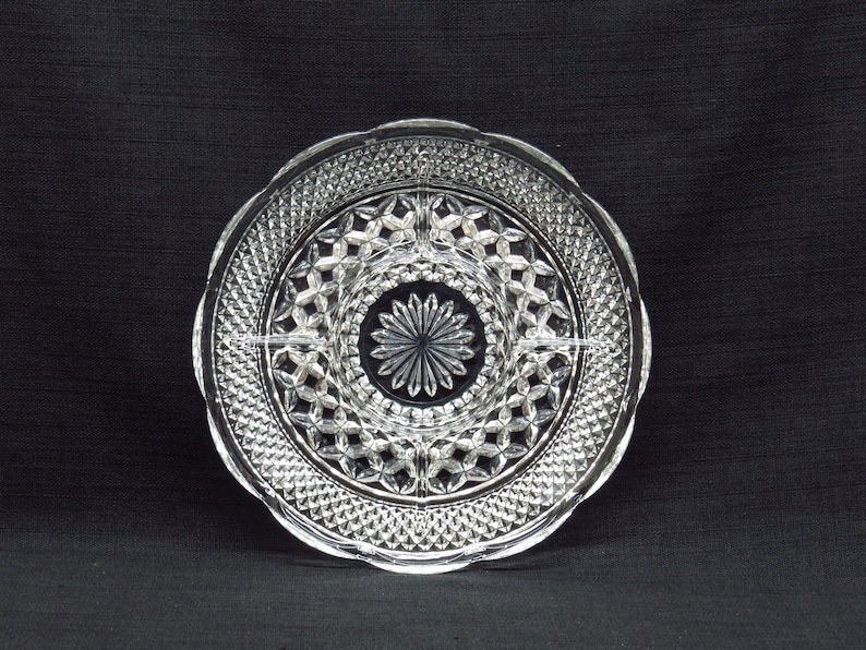 May include: A clear glass serving dish with a decorative, diamond-shaped pattern. The dish is divided into four sections.