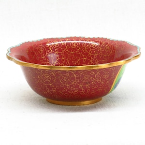 May include: A red and gold cloisonn&eacute; bowl with a scalloped rim and a floral design. The bowl is decorated with a peacock feather design on the side.