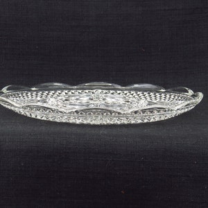 May include: A clear glass serving dish with a scalloped edge and a diamond pattern. The dish is oval shaped and has a raised centre section.