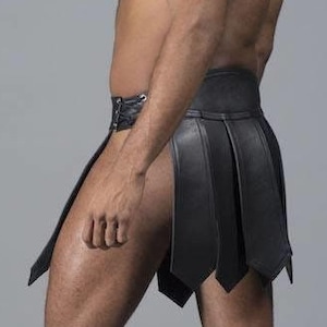 May include: Black leather skirt with a pleated design. The skirt has a high waist and a short length, with a buckle closure. The skirt is made of a smooth, shiny material.