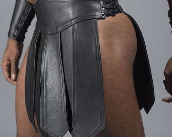 May include: Black leather gladiator skirt with vertical panels and a laced closure. The skirt features a wide waistband and is designed with a split on the side. A matching black leather arm cuff is also visible.