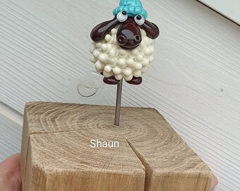 Shaun, the sheep in beige glass, on wooden block