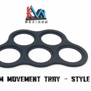 K&ouml;nnte beinhalten: Schwarzes Kunststofftablett mit f&uuml;nf runden Aussparungen, entworfen f&uuml;r die Aufnahme von 40 mm gro&szlig;en Miniaturen f&uuml;r Spiele. Das Tablett ist mit "40MM MOVEMENT TRAY - STYLE #1" beschriftet.