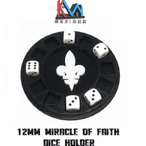May include: Black dice holder with a white fleur-de-lis design in the center, holding six white dice. The holder has slots for each die. The text "12MM MIRACLE OF FAITH DICE HOLDER" is printed at the bottom. The holder is a gaming accessory.
