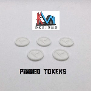 May include: Five white, circular tokens featuring a stylized letter "P" design. The tokens are arranged on a white surface. The text "PINNED TOKENS" is printed in a black, distressed font below the tokens. The KM Designs logo is at the top.