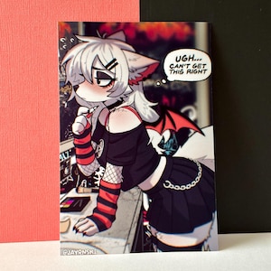 May include: A print featuring a stylized anthropomorphic wolf character in a black outfit with red accents. The character has white fur, a choker, and a thought bubble that reads "UGH... CAN'T GET THIS RIGHT". The print has a dark, edgy aesthetic.