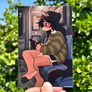 May include: A print featuring an anime-style character with animal features, wearing a green striped sweater and black shorts, seated on a subway car. The character is holding a phone, with a dark hat and tail. The background shows subway details.