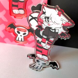 May include: An anime-style character with black wings and a skull on a black and white skull base. The character is wearing a black and red outfit with a black choker and a white cross.