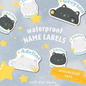 May include: Waterproof name labels with cute cat illustrations. The labels feature the names Adeline, Greyson, and Johnson. The labels are dishwasher safe.
