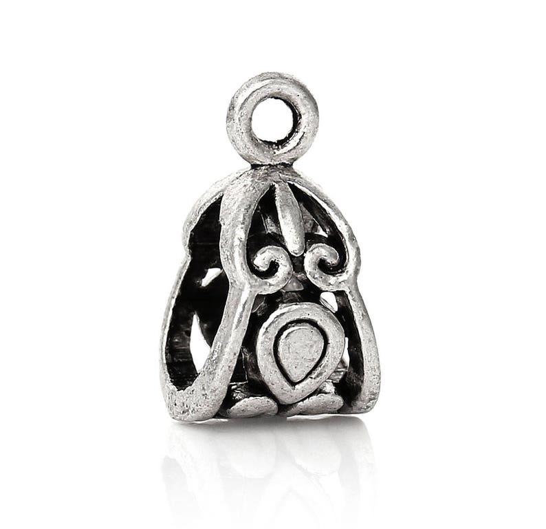 May include: Silver-toned metal pendant with an ornate design. The pendant has a loop at the top for attaching to a chain or cord.