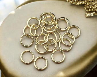 May include: A pile of gold-colored jump rings, a type of metal ring used in jewelry making.