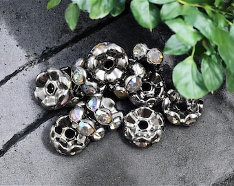 May include: A group of silver-toned metal beads with iridescent glass accents. The beads have a flower-like design with a hole in the center.