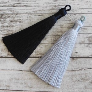 May include: Two tassels, one black and one silver, with a loop at the top for hanging.