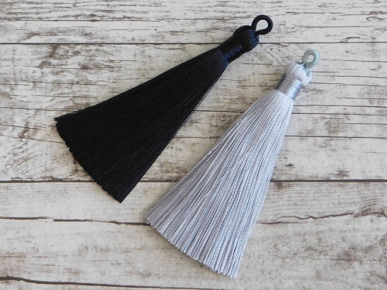 May include: Two tassels, one black and one silver, with a loop at the top for hanging.