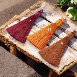 May include: Three tassel trims in different colors: burgundy, orange, and brown. The tassels are labeled with numbers 12, 11, and 4.