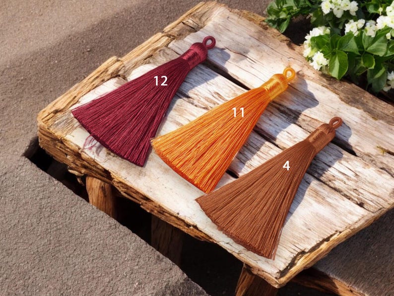 May include: Three tassel trims in different colors: burgundy, orange, and brown. The tassels are labeled with numbers 12, 11, and 4.
