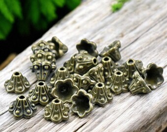 May include: A collection of antique gold metal beads with a decorative flower design. The beads are arranged on a wooden surface.