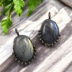 May include: Two oval-shaped labradorite gemstone pendants with a copper wire frame and copper bead accents.