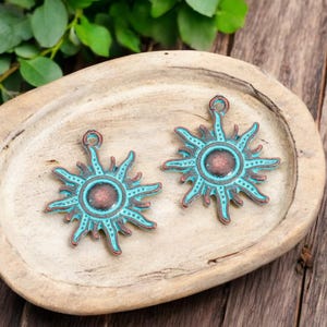 May include: Two turquoise blue metal sun charms with a copper center. The charms have a rustic, distressed look and are perfect for jewelry making.