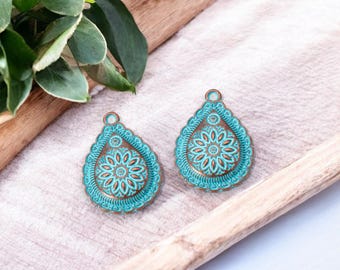 May include: Two turquoise blue teardrop-shaped metal charms with intricate copper-colored floral designs.
