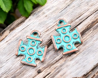 May include: Two turquoise blue metal cross charms with a copper finish and a circle pattern. The charms have a loop at the top for attaching to jewelry.
