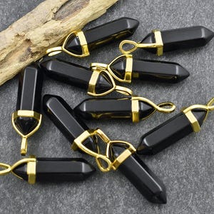 May include: A group of black gemstone pendants with gold accents. The pendants are shaped like points and have a polished finish.