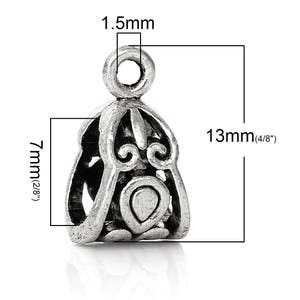 May include: Silver-toned metal pendant with an ornate design. The pendant is 13mm (1/2 inch) tall and 7mm (1/4 inch) wide. It has a loop at the top for attaching to a chain or cord.