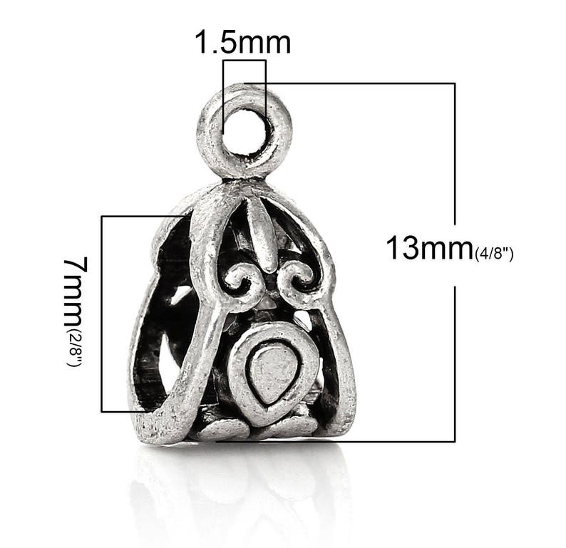 May include: Silver-toned metal pendant with an ornate design. The pendant is 13mm (1/2 inch) tall and 7mm (1/4 inch) wide. It has a loop at the top for attaching to a chain or cord.