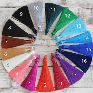 May include: A set of 17 colorful silk tassels with numbers 1 through 17. The tassels are arranged in a circle on a white wooden surface.