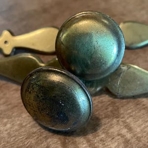 May include: Four antique brass door knobs with ornate handles. The knobs are round and have a worn, aged finish.