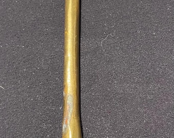 May include: A brass bottle opener shaped like a golf club. The opener has a loop at the top for leverage and a club head at the bottom. The brass has a slightly aged appearance.