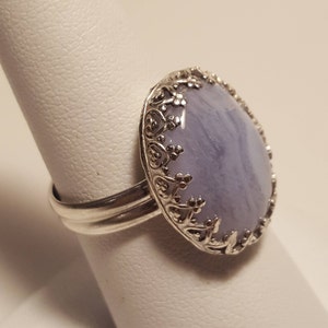 May include: A silver ring featuring a light blue agate stone set in a filigree design.