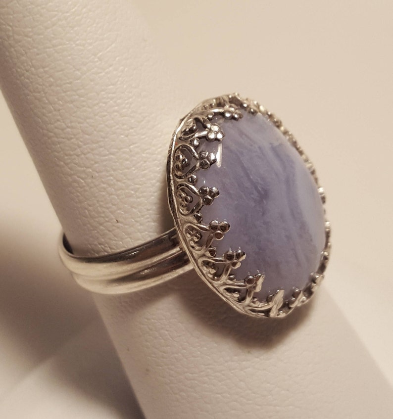 May include: A silver ring featuring a light blue agate stone set in a filigree design.