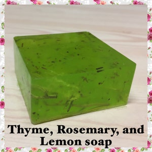 May include: A square, translucent green soap bar with visible thyme and rosemary inclusions. The soap has the text "Thyme, Rosemary, and Lemon soap" at the bottom. The soap is a vibrant green color.