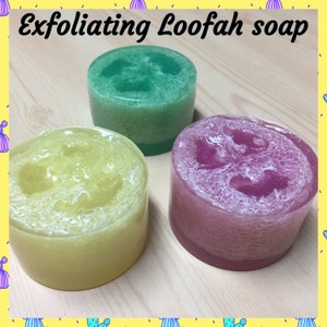 May include: Three exfoliating loofah soaps in green, yellow, and purple. The soaps are round and have a textured surface.