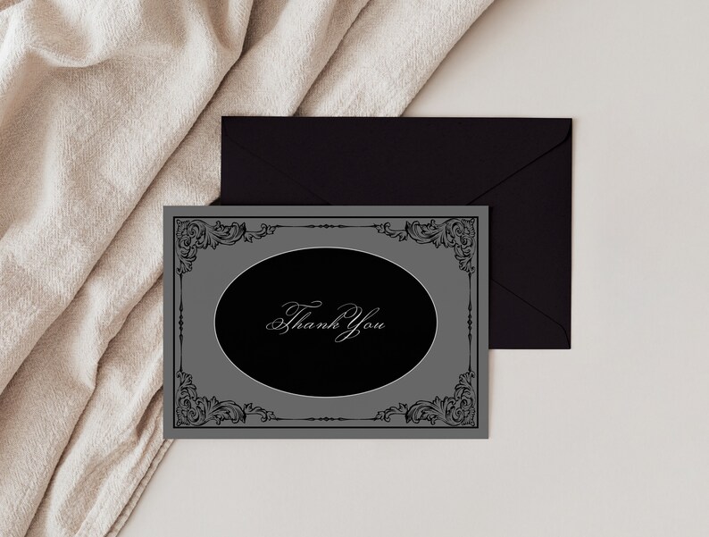 May include: A gray thank you card with a black oval in the center. The oval has a white cursive inscription that says "Thank You". The card is framed with a black ornate design.