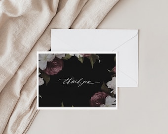 May include: A black thank you card with a floral border of white and purple flowers. The text "thank you" is written in white calligraphy.