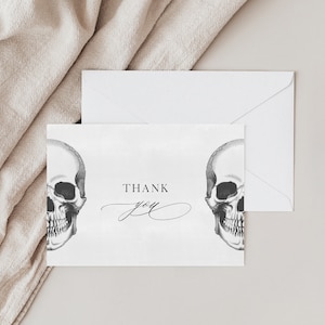 May include: A white thank you card with two black and white skull illustrations and the text "THANK YOU" in black.