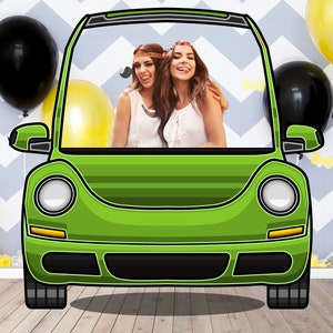 May include: Two women wearing flower crowns are posing in a green Volkswagen Beetle photo booth cutout. The cutout has a black frame and a white background. The women are smiling and looking at the camera. There are balloons in the background.