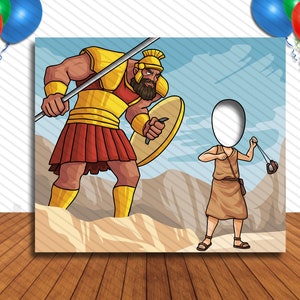 May include: A cartoon illustration of a giant warrior holding a spear and shield, facing a smaller figure holding a slingshot. The smaller figure has a blank space for a face, making it a photo booth prop.