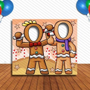 May include: Two gingerbread people photo booth cutouts with blank faces for guests to put their faces through. The gingerbread people are wearing red and purple scarves and holding candy canes.