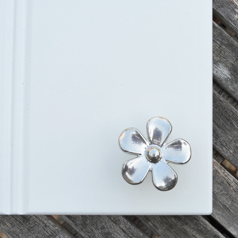 May include: Silver flower-shaped cabinet knob with a raised centre.