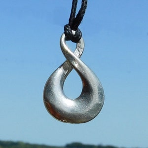 May include: A silver infinity symbol pendant on a black cord necklace. The pendant is smooth and shiny.