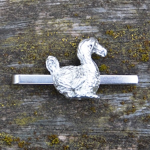 Könnte beinhalten: Ein silberner Krawattenclip mit einer detaillierten, dreidimensionalen Skulptur eines Dodos.